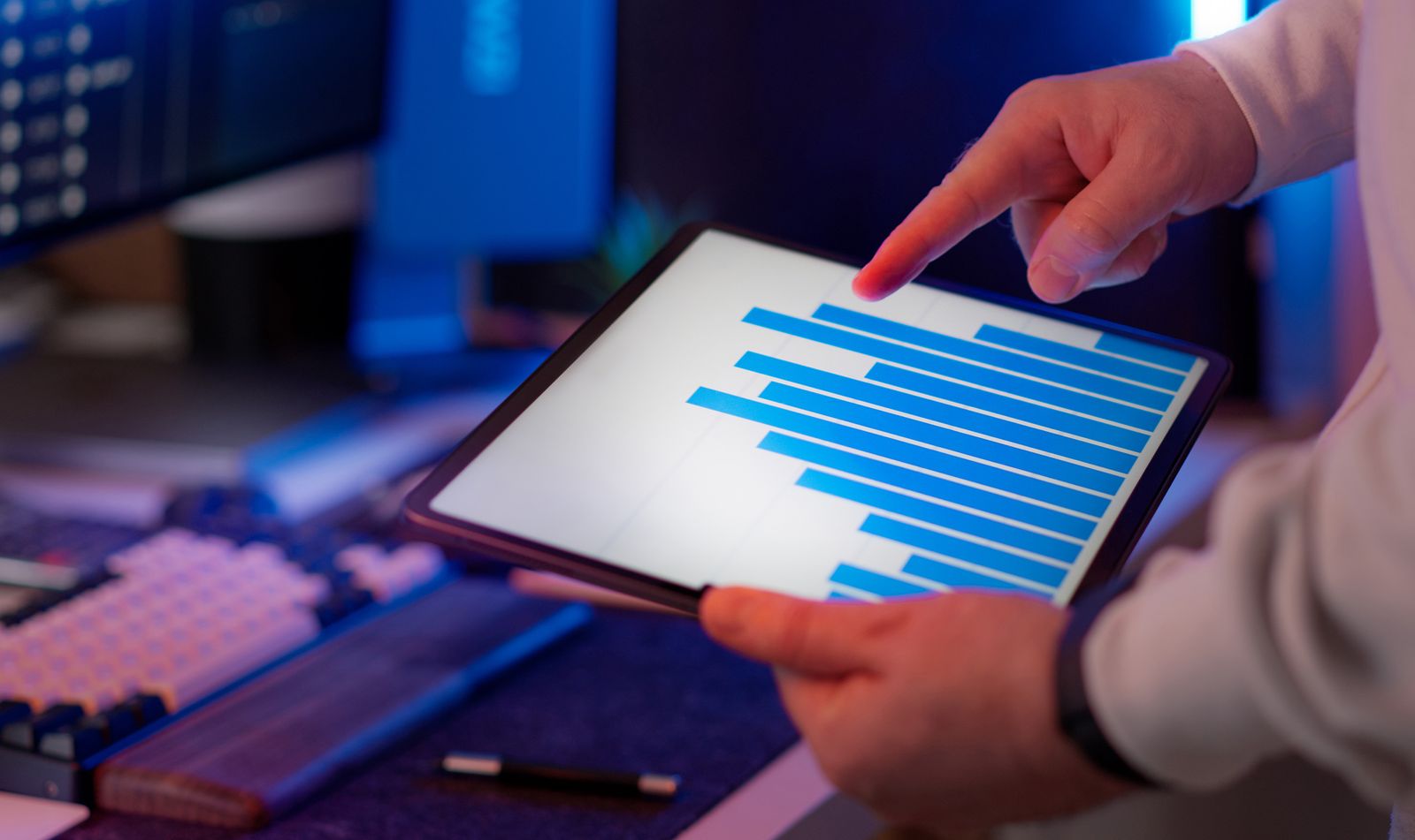 Person pointing at a bar chart on a tablet